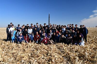 the Illinois Space  Socitey team posed in a cornfield with rocket
