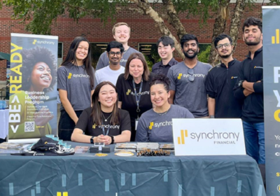 Synchrony interns and employees at a table at an internship job fair at Research Park