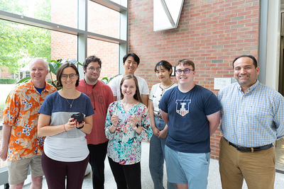 group of researchers pose in lobby with device
