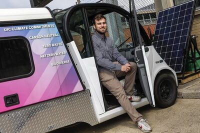student sits in doorway to electric vehicle