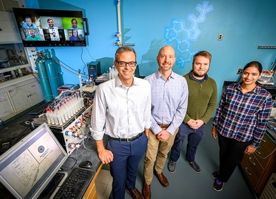 Pictured, from left: University of Illinois chemistry professor Martin D. Burke, materials science and engineering professor Charles M. Schroeder, graduate student Nicholas Angello and postdoctoral researcher Vandana Rathore. Pictured on the screen behind them are international collaborators, led by professors Bartosz A. Grzybowski and Alán Aspuru-Guzik.