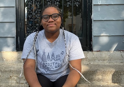 Aijah Welch sits on porch steps wearing her gray Digital Scholars t-shirt