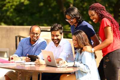 UIC students crowded around laptop at outdoor table