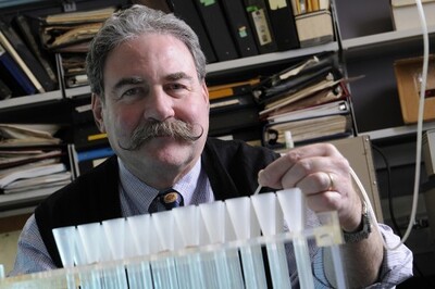 Man with handlebar mustache in office with test tubes