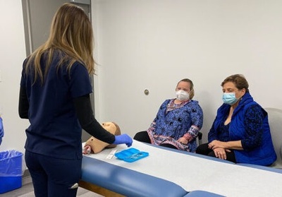 Student cconduct a simulated exam involving a manikin and a standardized patient played by Bridget Brown in the UIC Nursing Schwartz Lab. Brown’s mom, Nancy (far right), acts as the patient’s health coach.