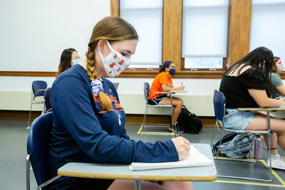 female student wearing Illini mask at desk in classroom