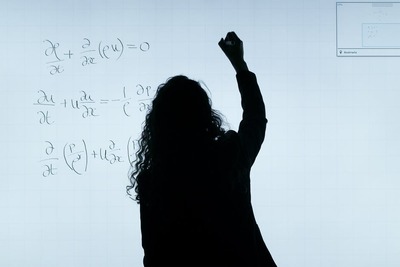 shadow of female professor writing on white board