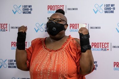 Lorraine Brown with arms in air and mask on celebrating vaccination