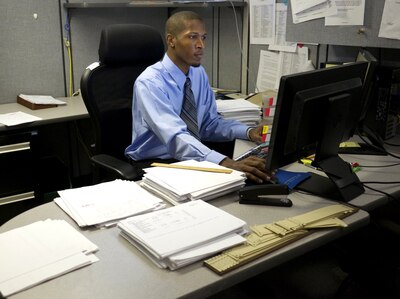 man in shirt and tie working at a desk on computer
