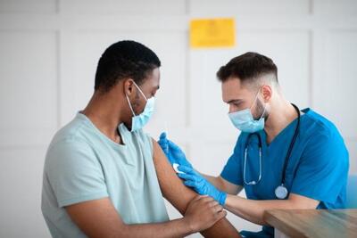 Black male being vaccinated by white male