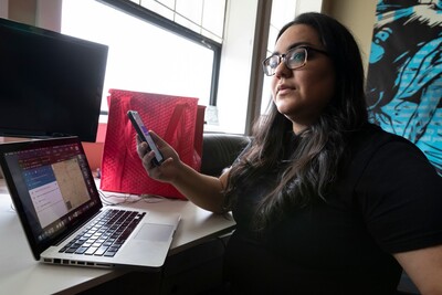 Anna Lopez works on laptop and mobile phone at desk